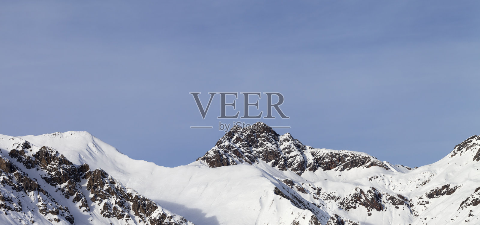 冬季高山与积雪的岩石和晴朗的天空的全景照片摄影图片