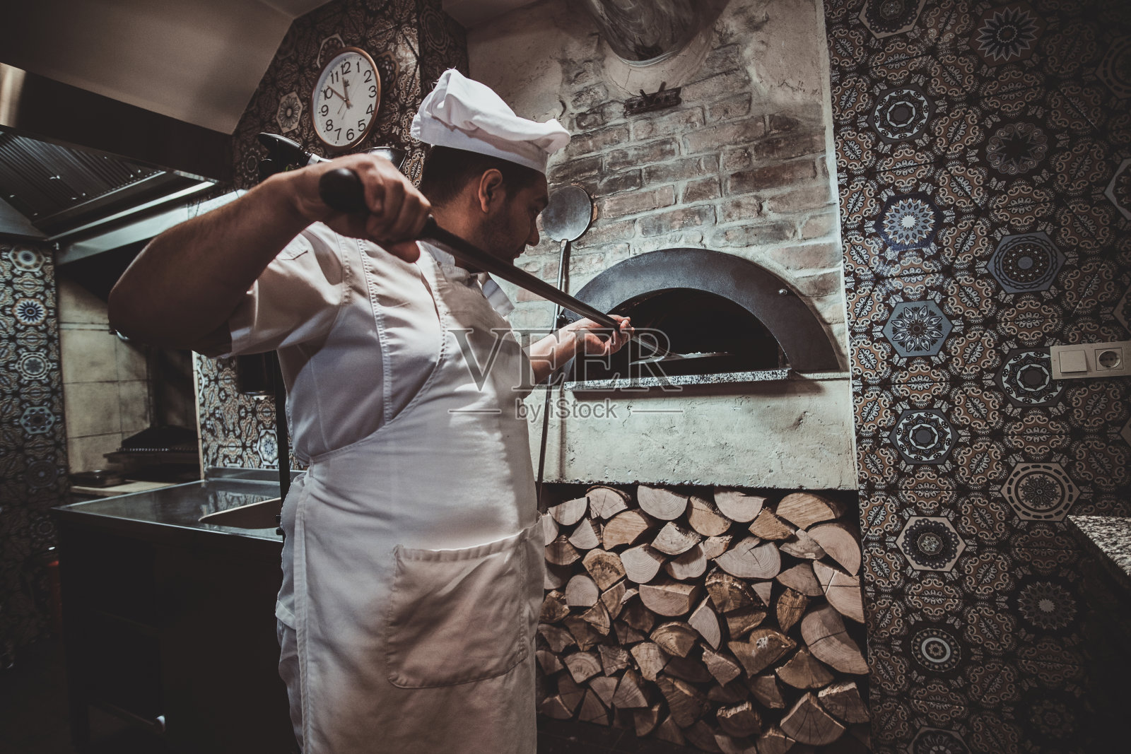 厨师正在将披萨放入烤箱照片摄影图片