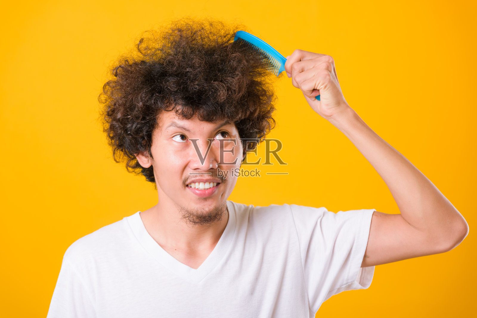 亚洲男子用黄色梳理卷曲的头发照片摄影图片