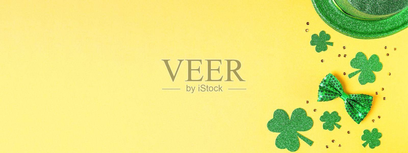 圣帕特里克节的节日卡片上有绿色的三叶草标志，帽子，金色的纸屑。传统的圣帕特里克节绿色服装和黄色背景的装饰。网页横幅，拷贝空间照片摄影图片