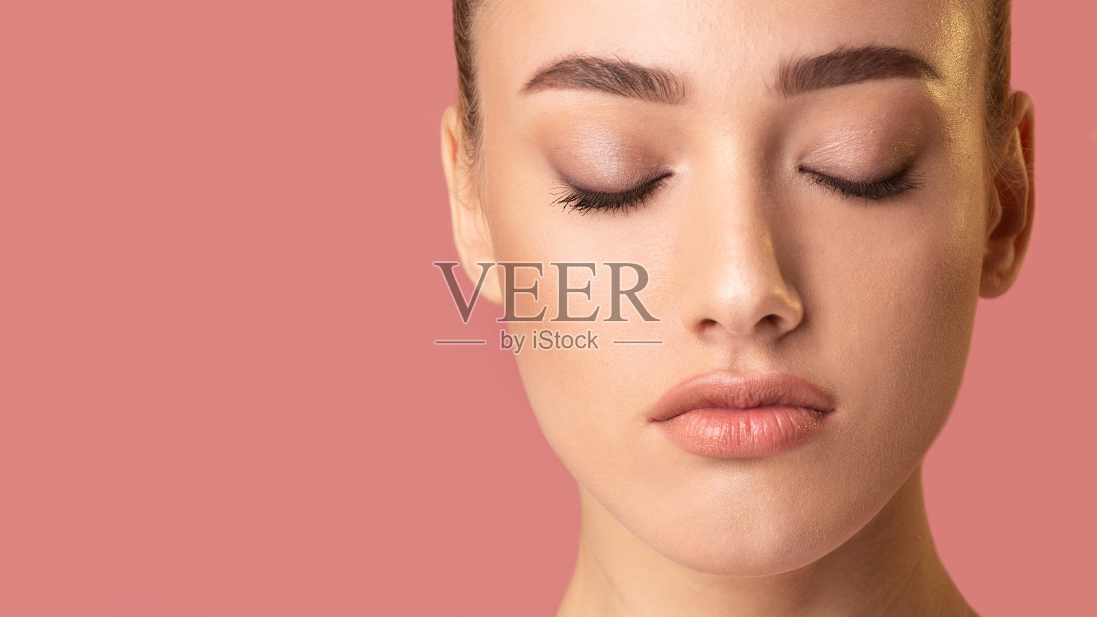 闭着眼睛的女人在粉红色的工作室背景下摆姿势，全景照片摄影图片