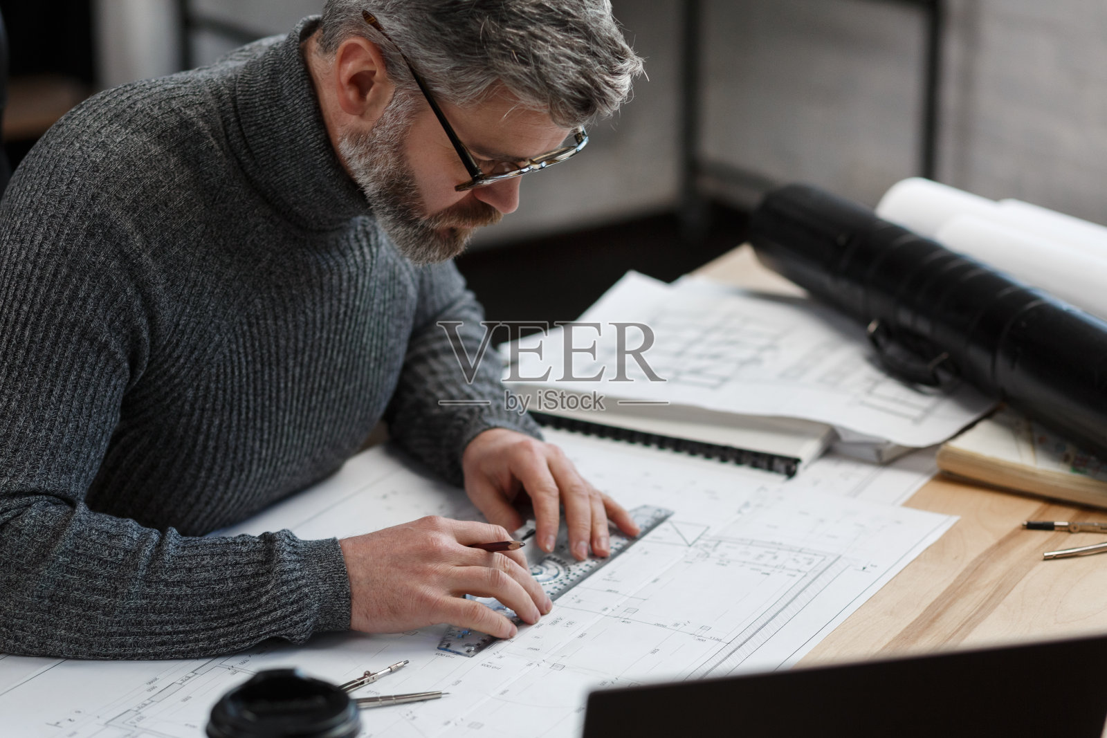 建筑师在办公室绘制蓝图，工程师绘制建筑项目草图，建筑平面图，英俊的胡须男专注于工作特写，商业建筑概念照片摄影图片