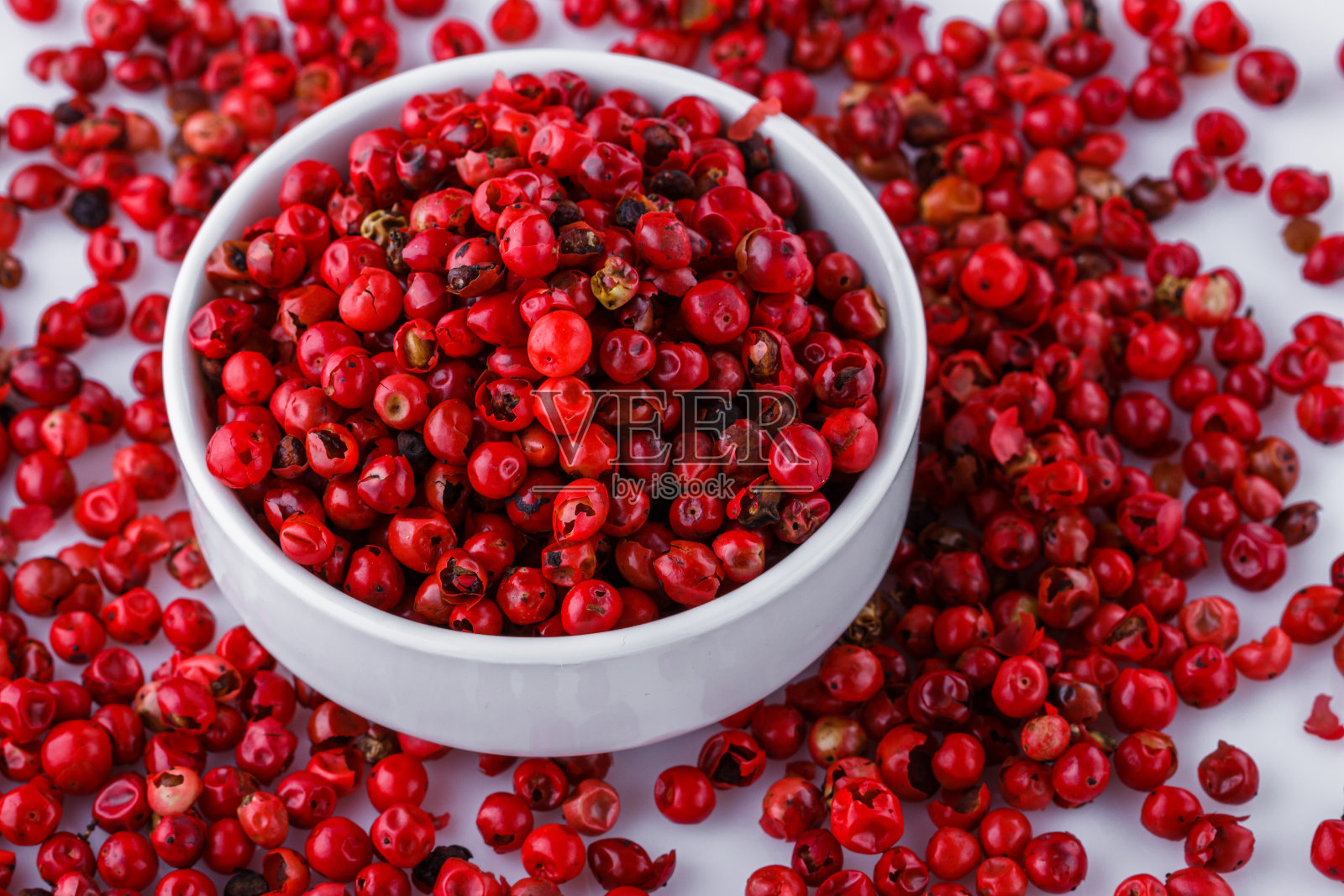 白色的丙烯酸背景上点缀着芬芳的粉色花椒照片摄影图片