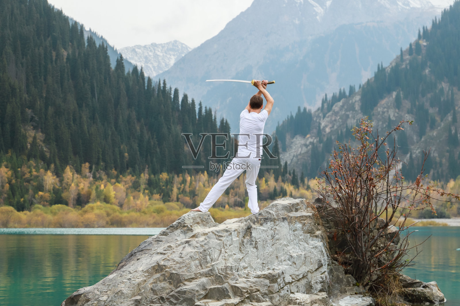 男人头顶上方举着一把日本武士刀，训练格斗技能照片摄影图片
