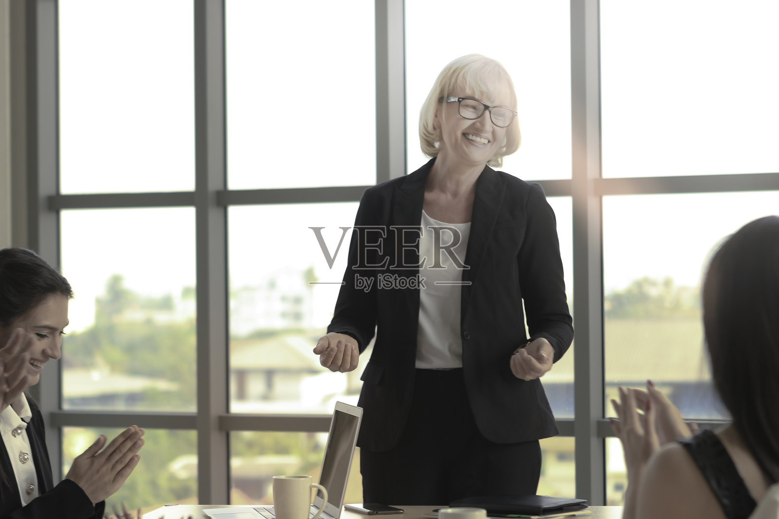 成功的年长女商人因在会议上做完报告后获得赞赏，企业团队鼓掌并赞赏好结果照片摄影图片