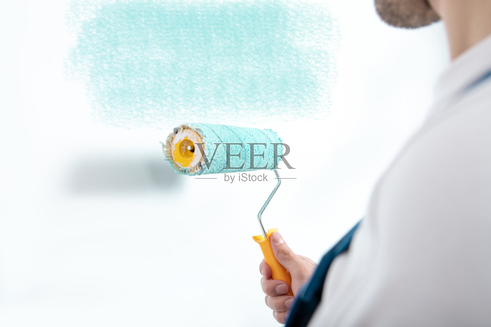 年轻男子用滚筒粉刷墙壁照片摄影图片