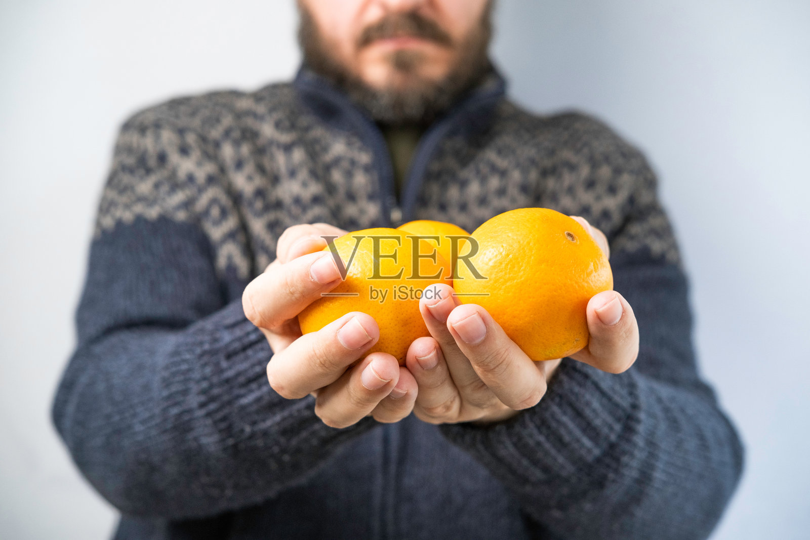 穿着毛衣递橘子的男人照片摄影图片