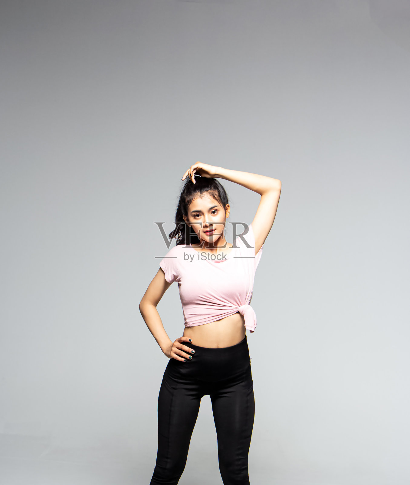 穿着运动服的女人，举起左手触摸头部，准备跳舞，模特摆姿势照片摄影图片