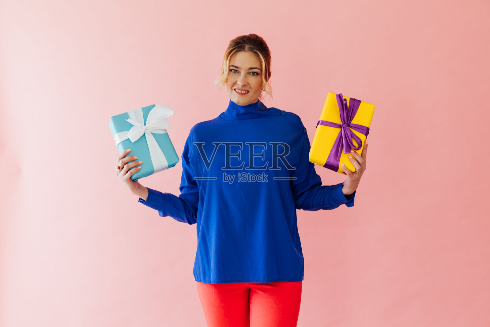 粉色背景下拿着礼物的40岁美女照片摄影图片