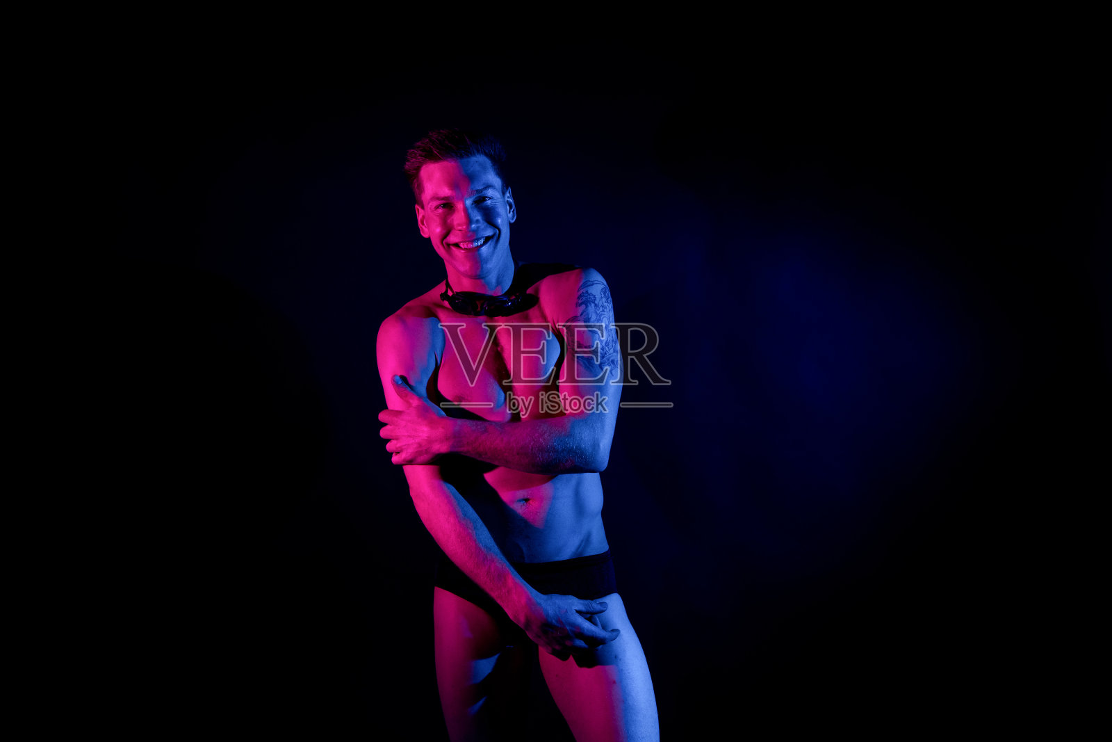 白人男性穿着泳裤在黑色背景前游泳照片摄影图片