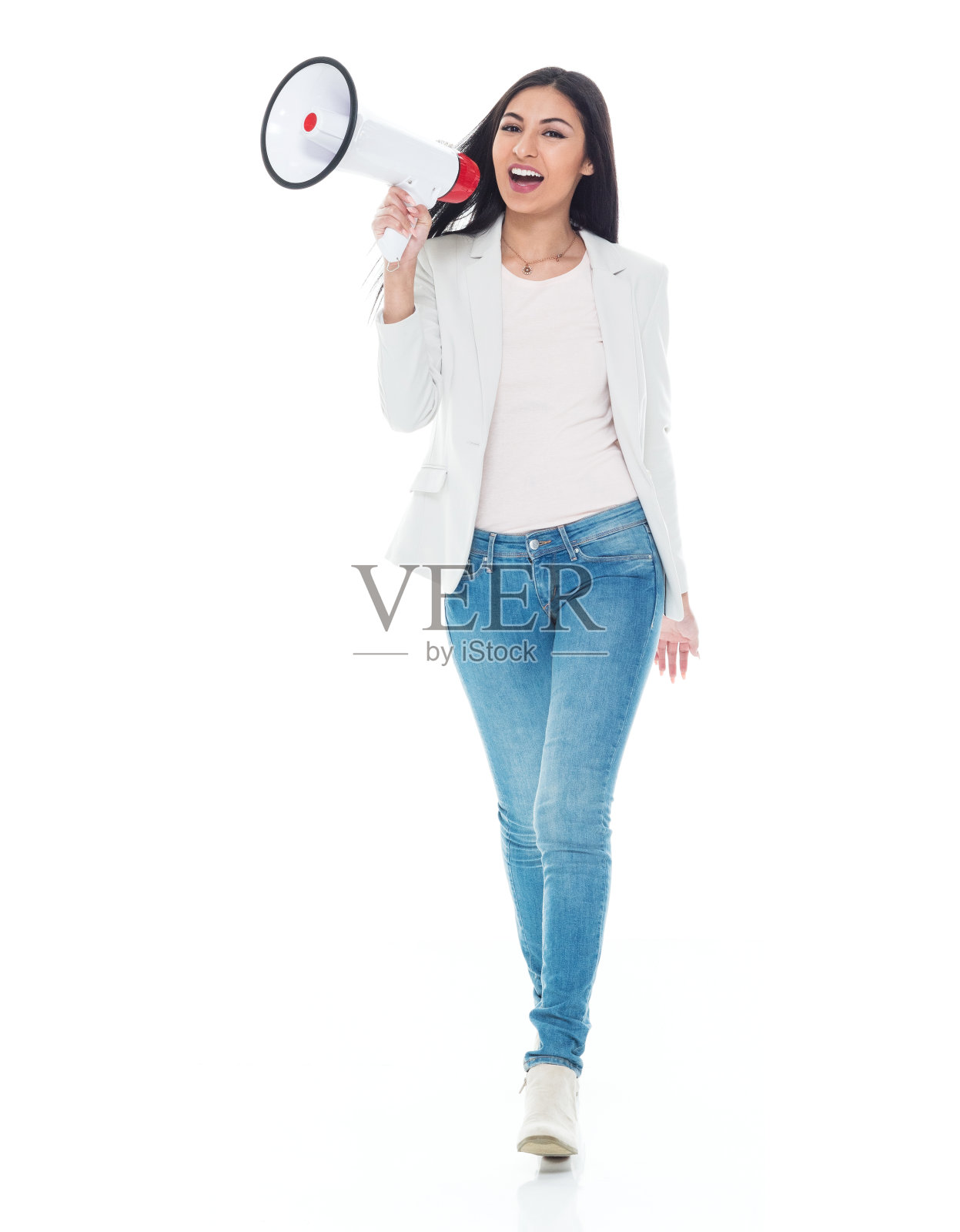 拉丁美洲和西班牙裔女性穿着牛仔裤，手持扩音器走在白色背景前照片摄影图片