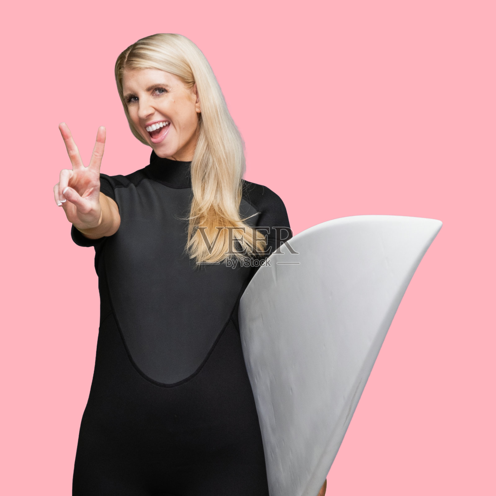 白人女性在有色背景前穿着潜水服，使用冲浪板照片摄影图片