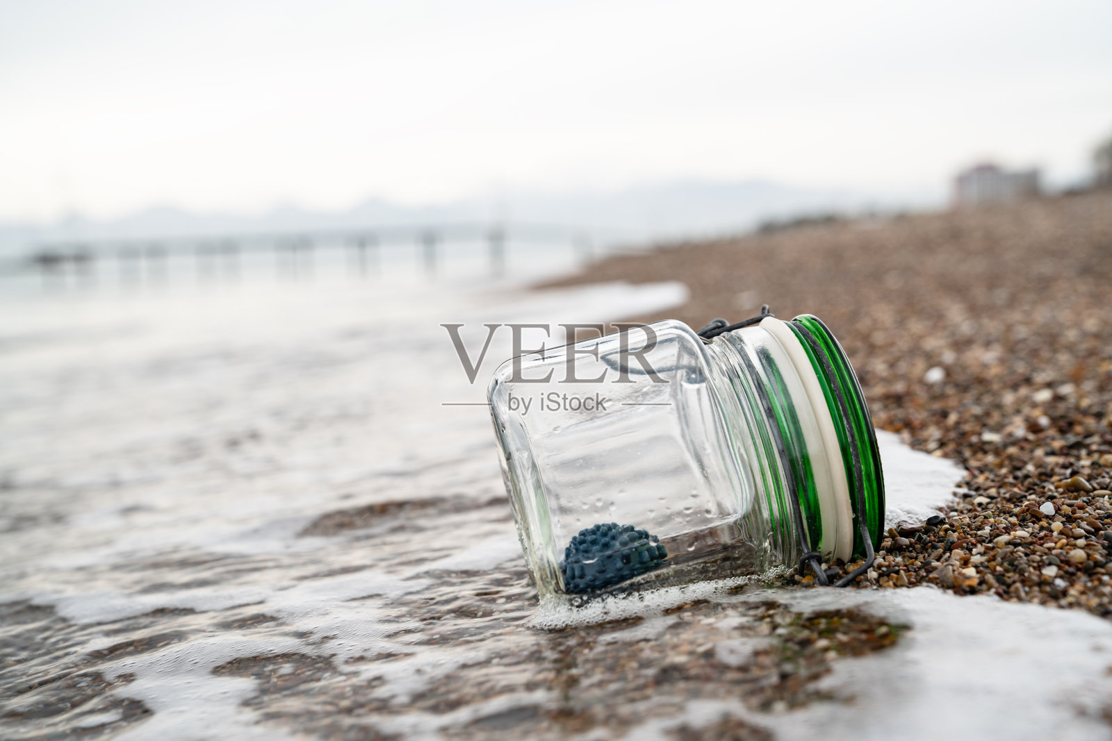沙滩上装有病毒形状的球的瓶子照片照片摄影图片