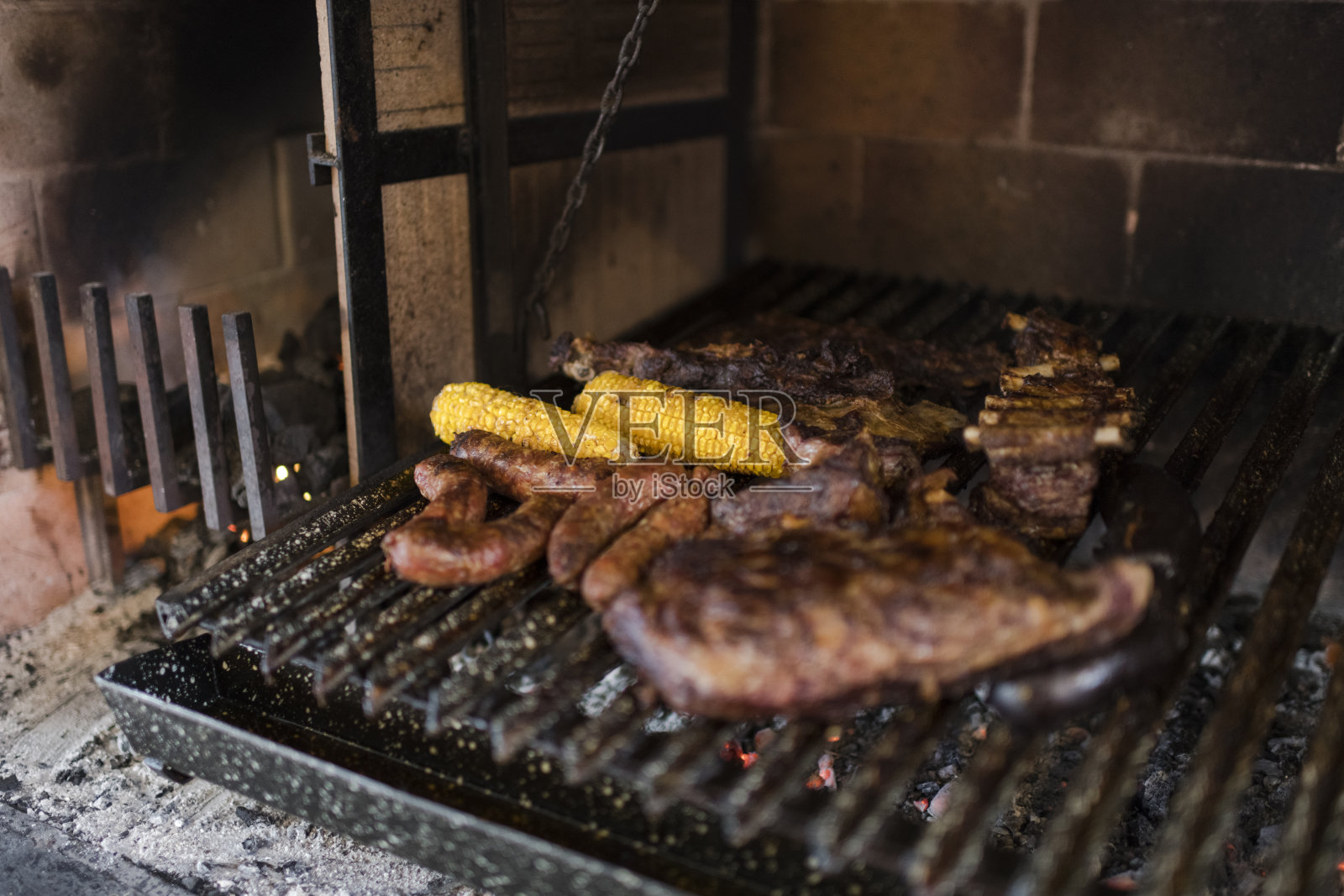 各种煮熟的肉、香肠和玉米棒放在烧烤架上照片摄影图片