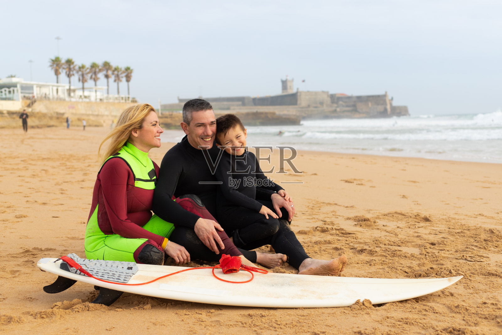 幸福的一家人带着冲浪板在海滩上照片摄影图片