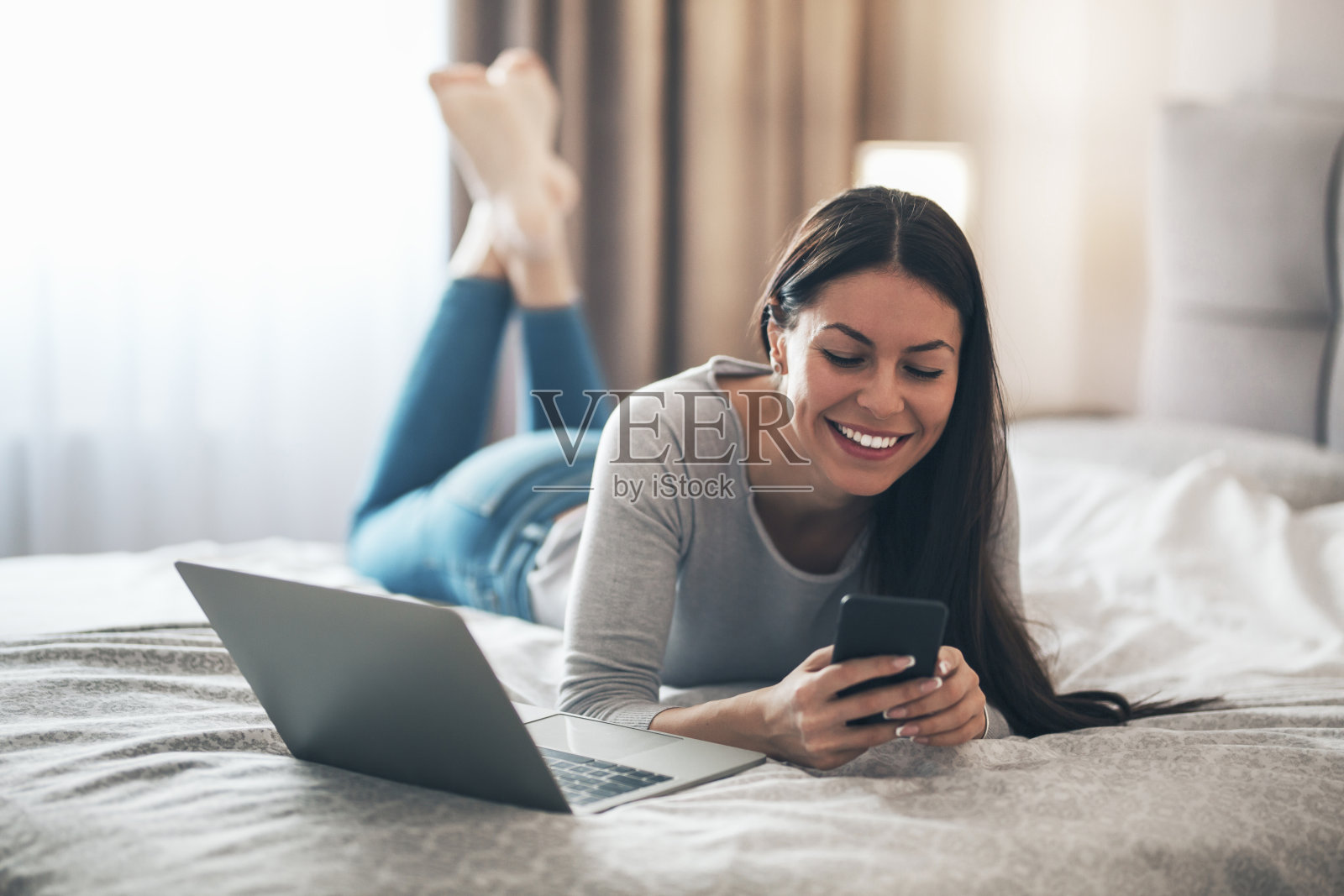 女孩躺在床上用手机打字照片摄影图片