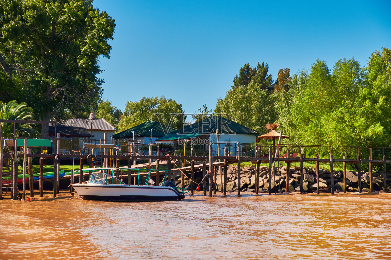 阿根廷蒂格拉三角洲，从首都布宜诺斯艾利斯以北的巴拉那河三角洲水系。郁郁葱葱的植被，木制的房子。码头旁有摩托艇。卢江三角洲水系橙色黏土水照片摄影图片
