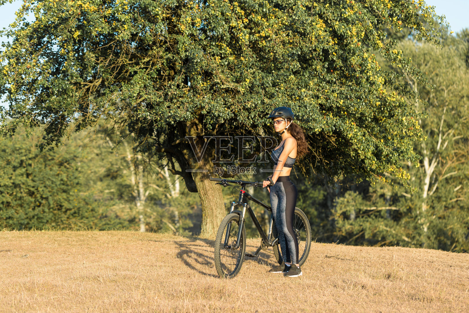 女孩在越野山地车，美丽的肖像自行车在日落，健身女孩骑现代碳纤维山地车。照片摄影图片