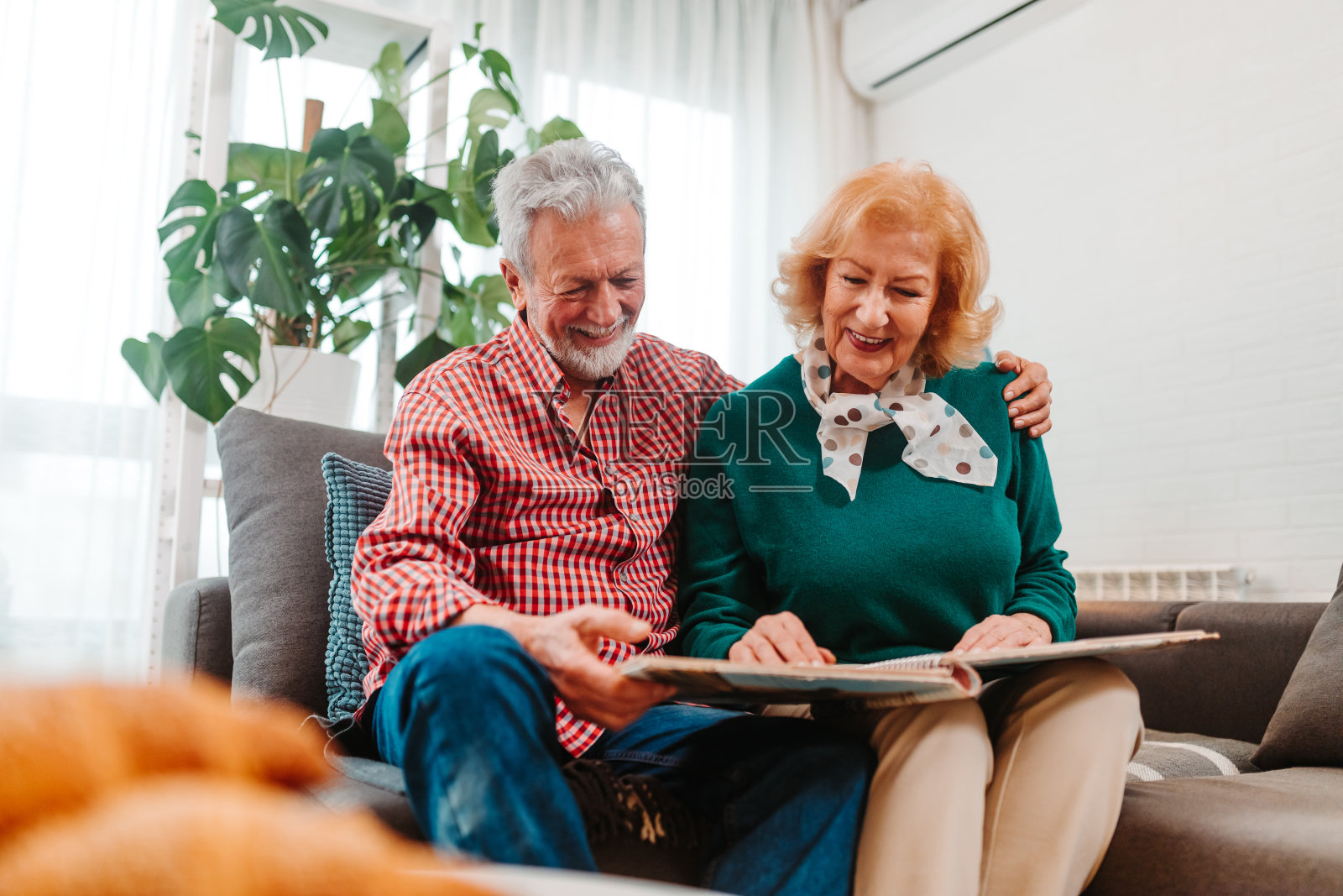 丈夫拥抱妻子，一起回忆相册里的记忆。老夫妇在客厅里追忆往事照片摄影图片