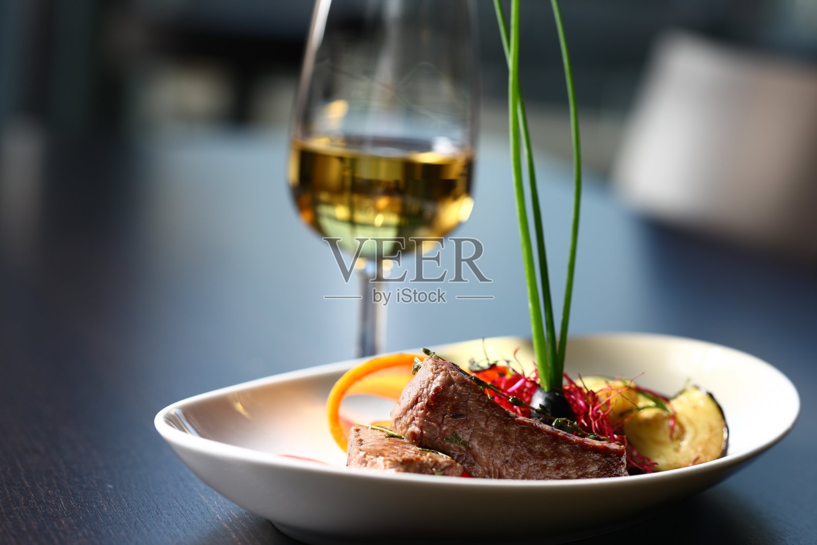餐厅的餐桌上有美味的食物。肉，一杯绿叶子的酒放在灰色的桌面上照片摄影图片