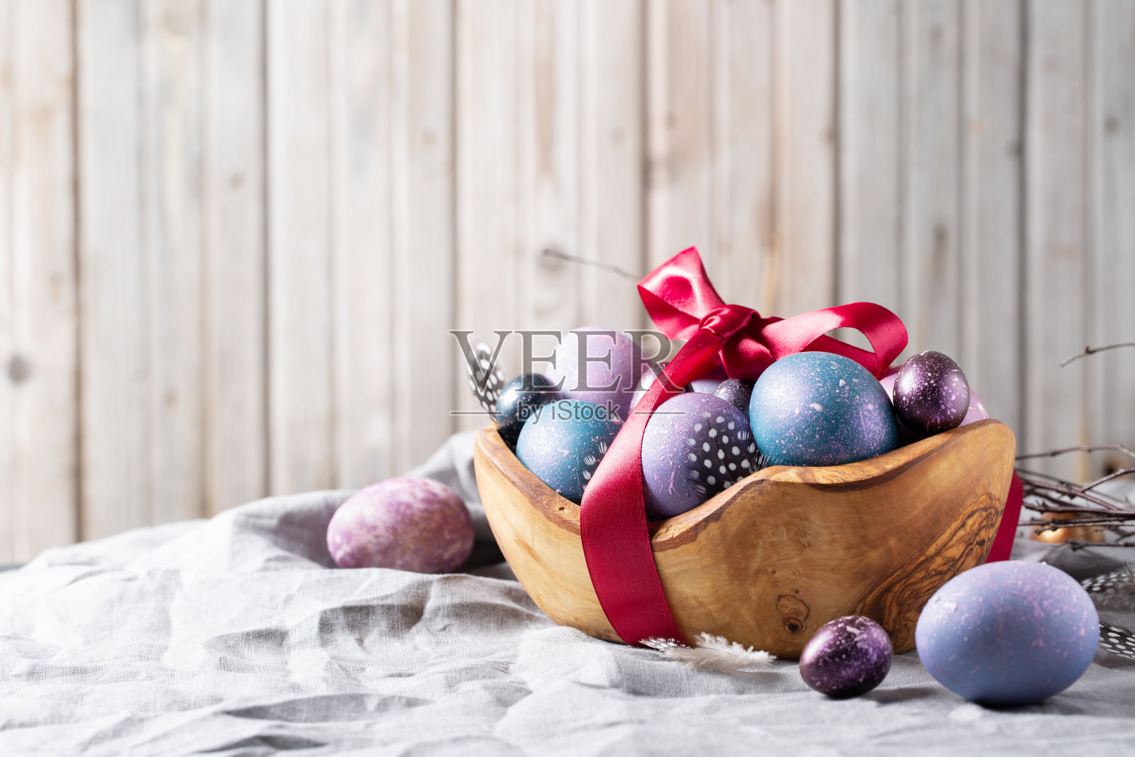 复活节。节日的彩蛋放在一个木制的碗里，背景是灰色的棉布。空间的文本。照片摄影图片