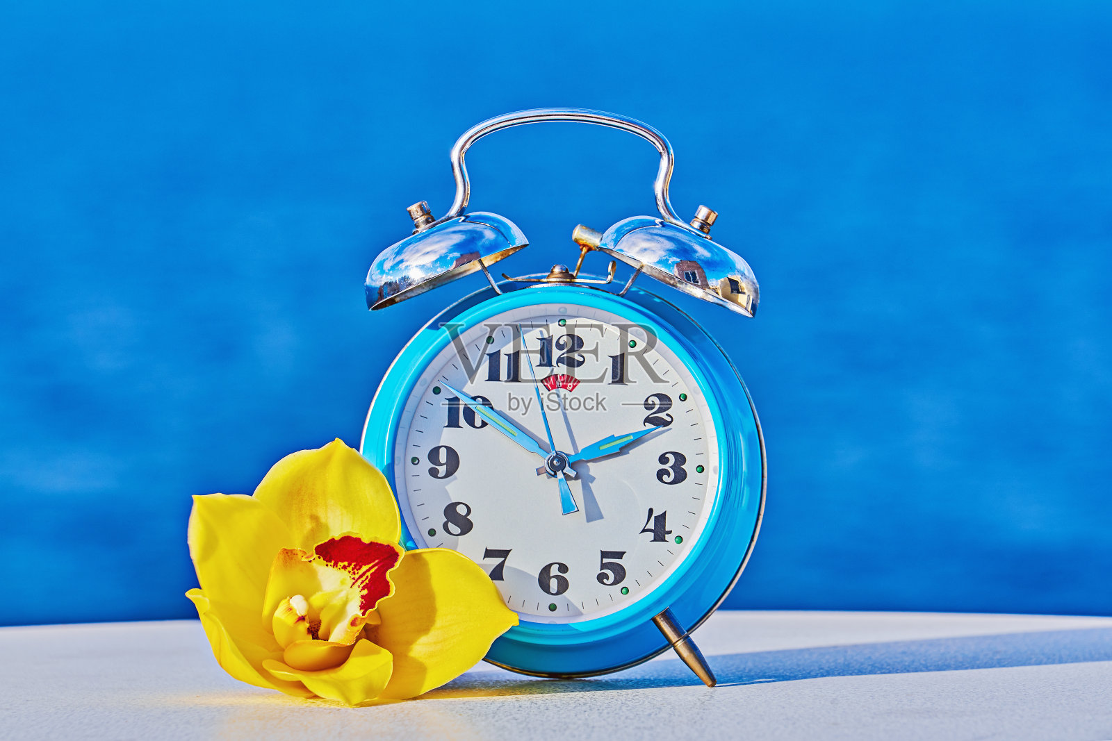 以海洋为背景的蓝色闹钟，采用了春季向前和夏令时的概念照片摄影图片