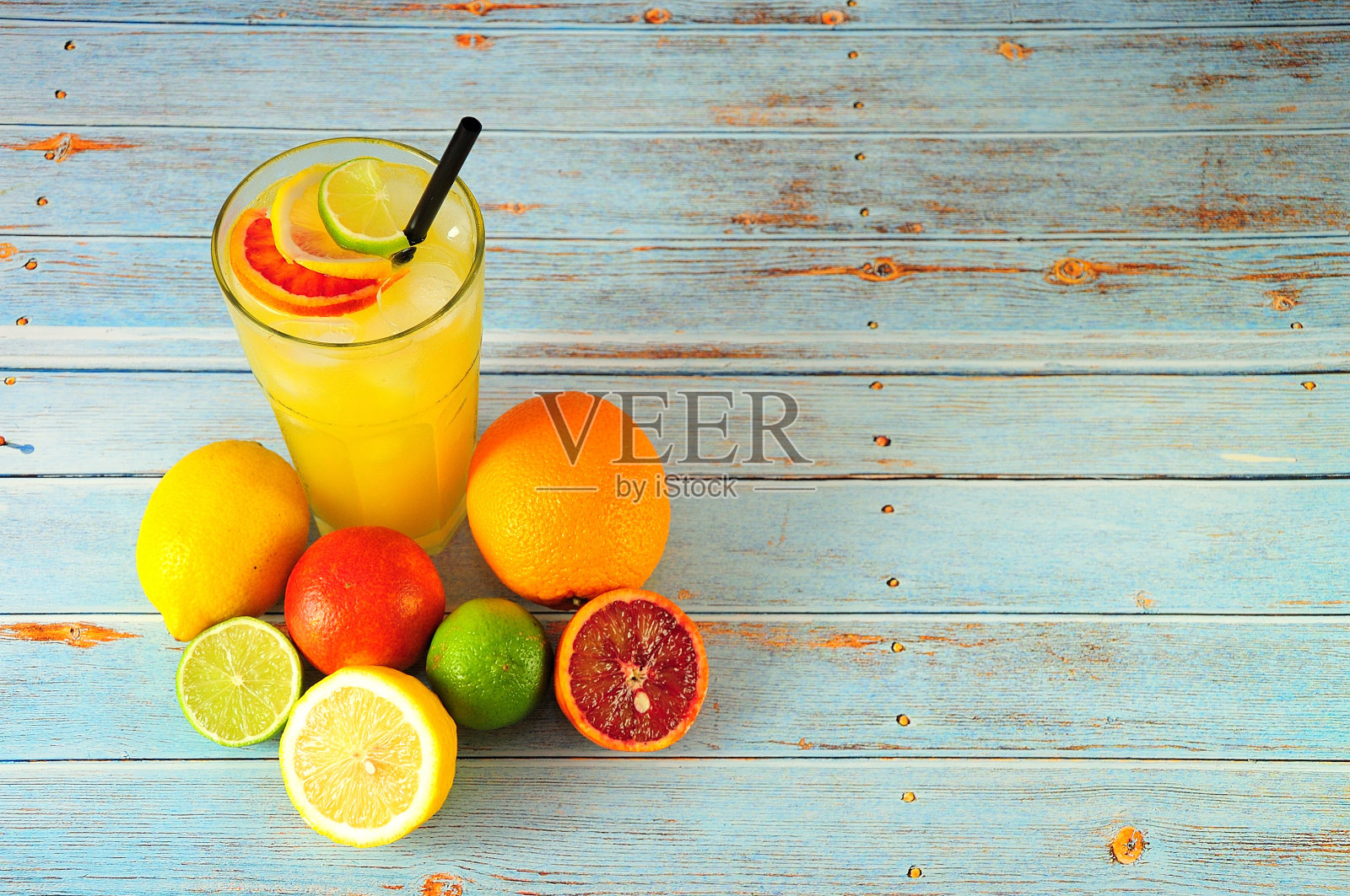用高脚杯加冰混合柑橘，旁边放着酸橙、柠檬、橙子和葡萄柚，放在木桌上。照片摄影图片