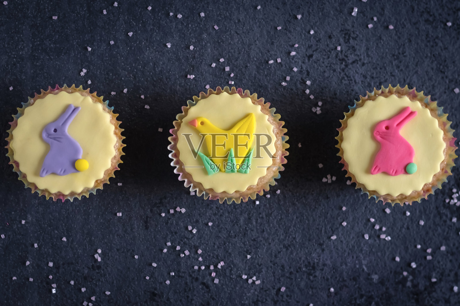 色彩缤纷，相当素食复活节纸杯蛋糕与糖霜形状的复活节兔子和小鸡的黑色石板背景照片摄影图片