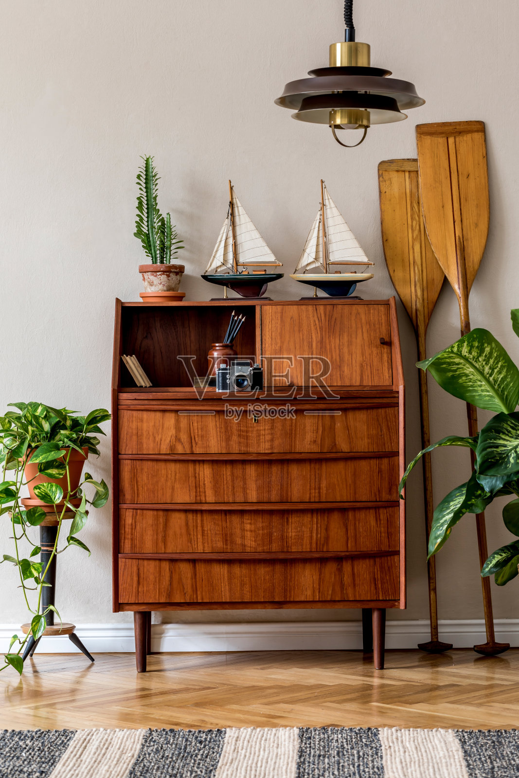 时尚复古的客厅室内设计，木制复古马桶，植物，船，桨，吊灯和优雅的个人饰品。模板。米色墙。复古的家居装饰理念。照片摄影图片