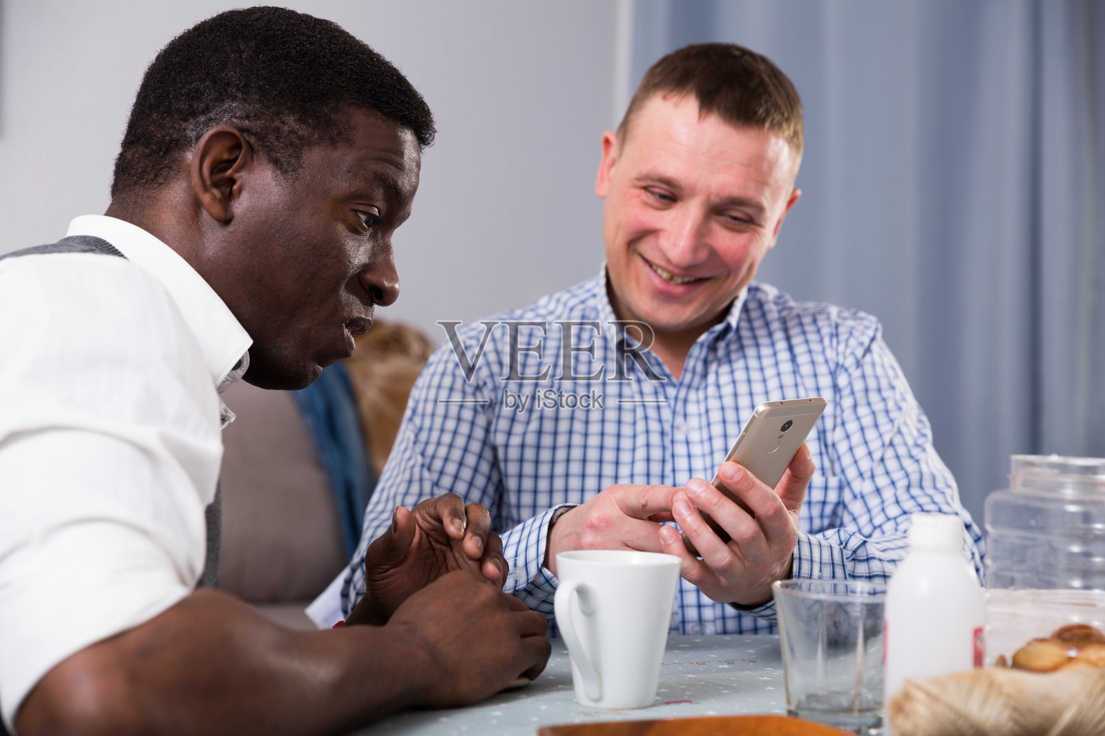 在家与非洲朋友用手机交谈的微笑男人照片摄影图片