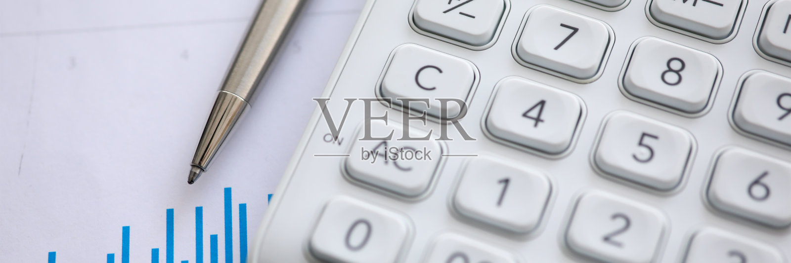 白色计算器和银色笔放在图表上照片摄影图片