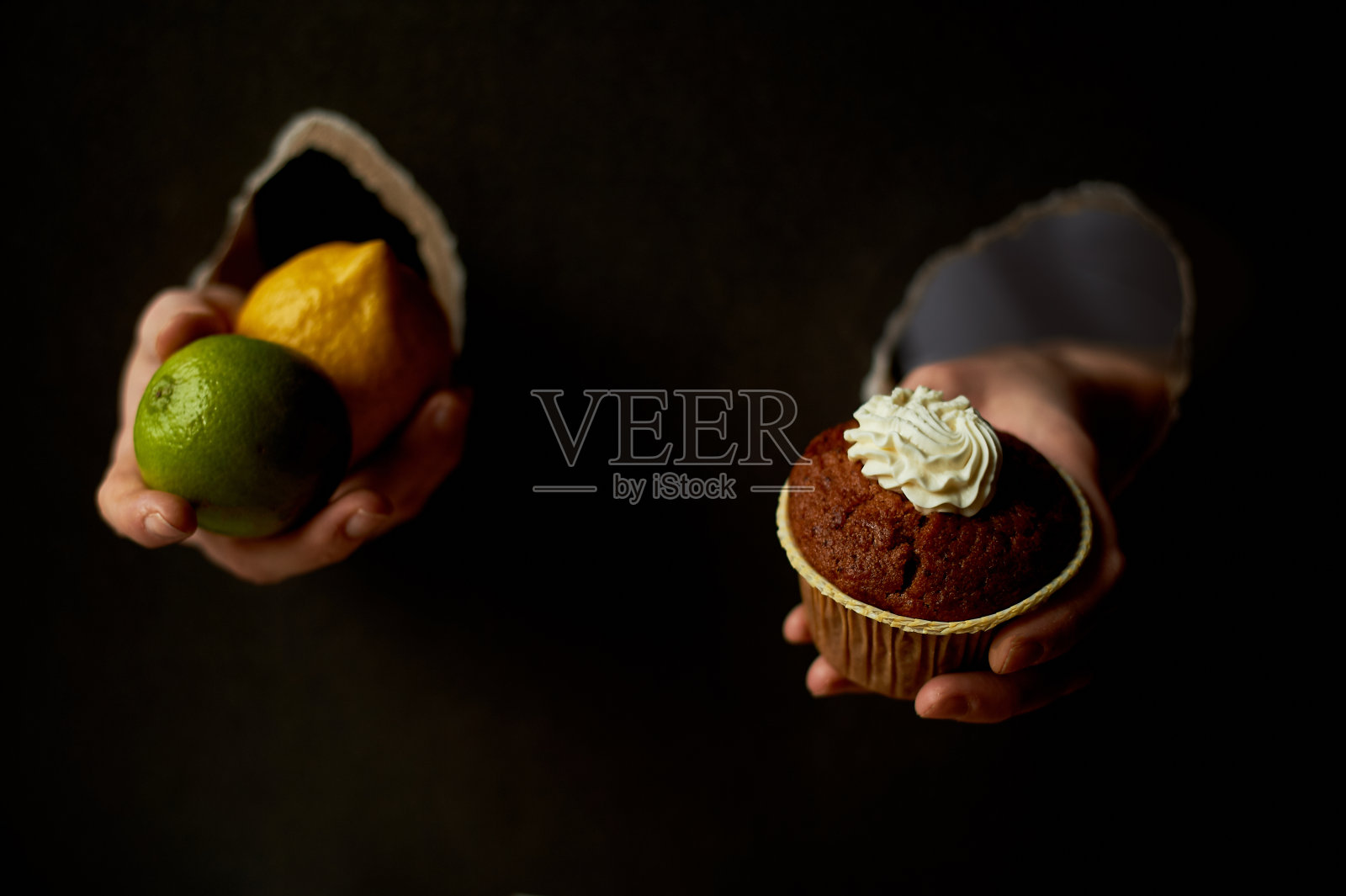 拼贴画。把纸的孔交进去。拿着一个纸杯蛋糕和一个柠檬。对着甜美的果实。饮食或暴食。趋势，文本的位置照片摄影图片