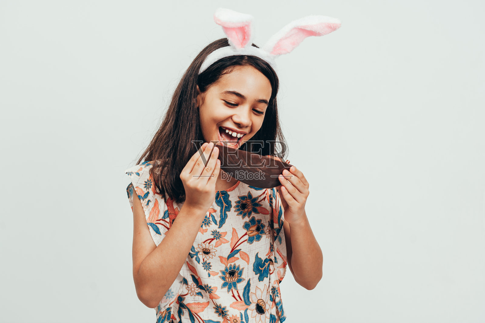 甜美的小女孩戴着兔子耳朵吃巧克力复活节彩蛋。复活节在巴西照片摄影图片