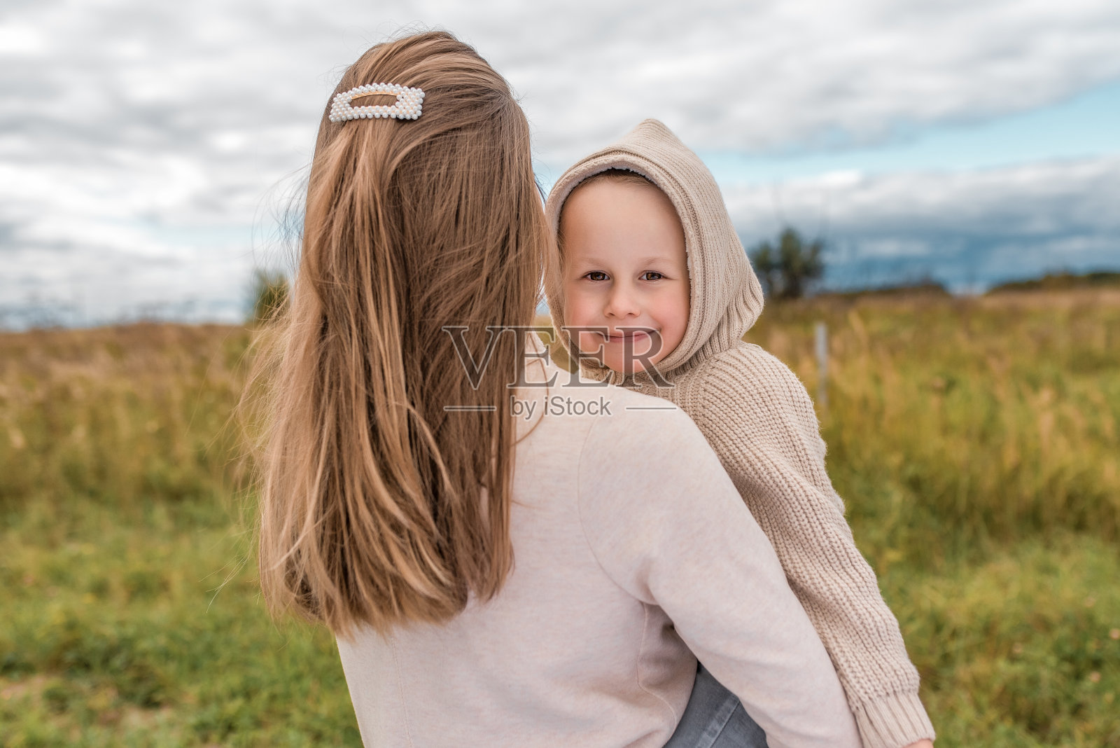 秋日里，妈妈抱着小男孩在夏日漫步，充满关爱，支持和爱。快乐的宝宝在微笑，享受舒适和放松的周末照片摄影图片