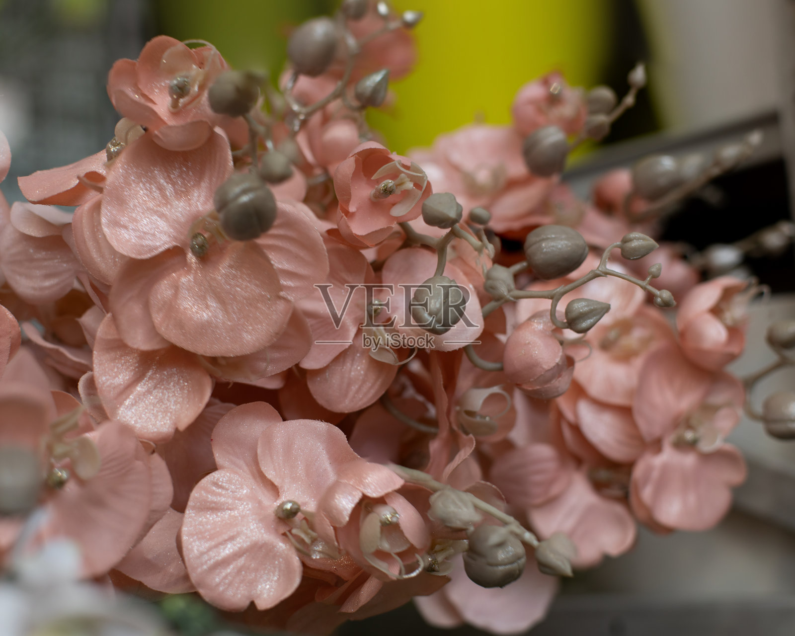 粉红色的人造花烤饼与花蕾上的一个分支，背景背景装饰设计的特写。一束假花用于室内装饰照片摄影图片