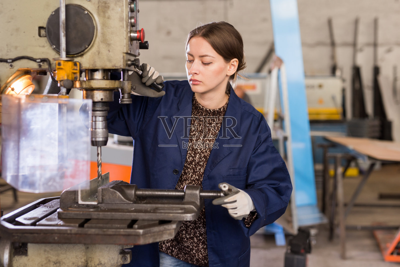 在车间使用钻机的自信女机械师照片摄影图片
