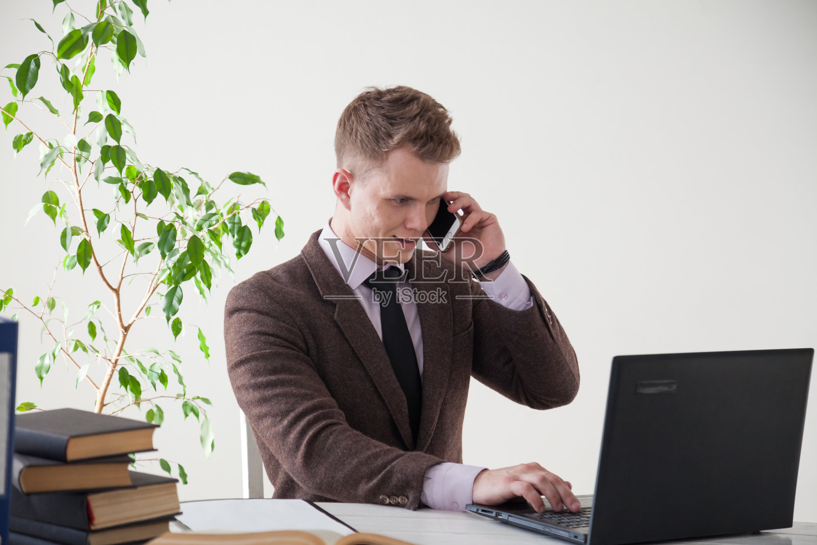 男子在办公室用电脑工作并打电话照片摄影图片
