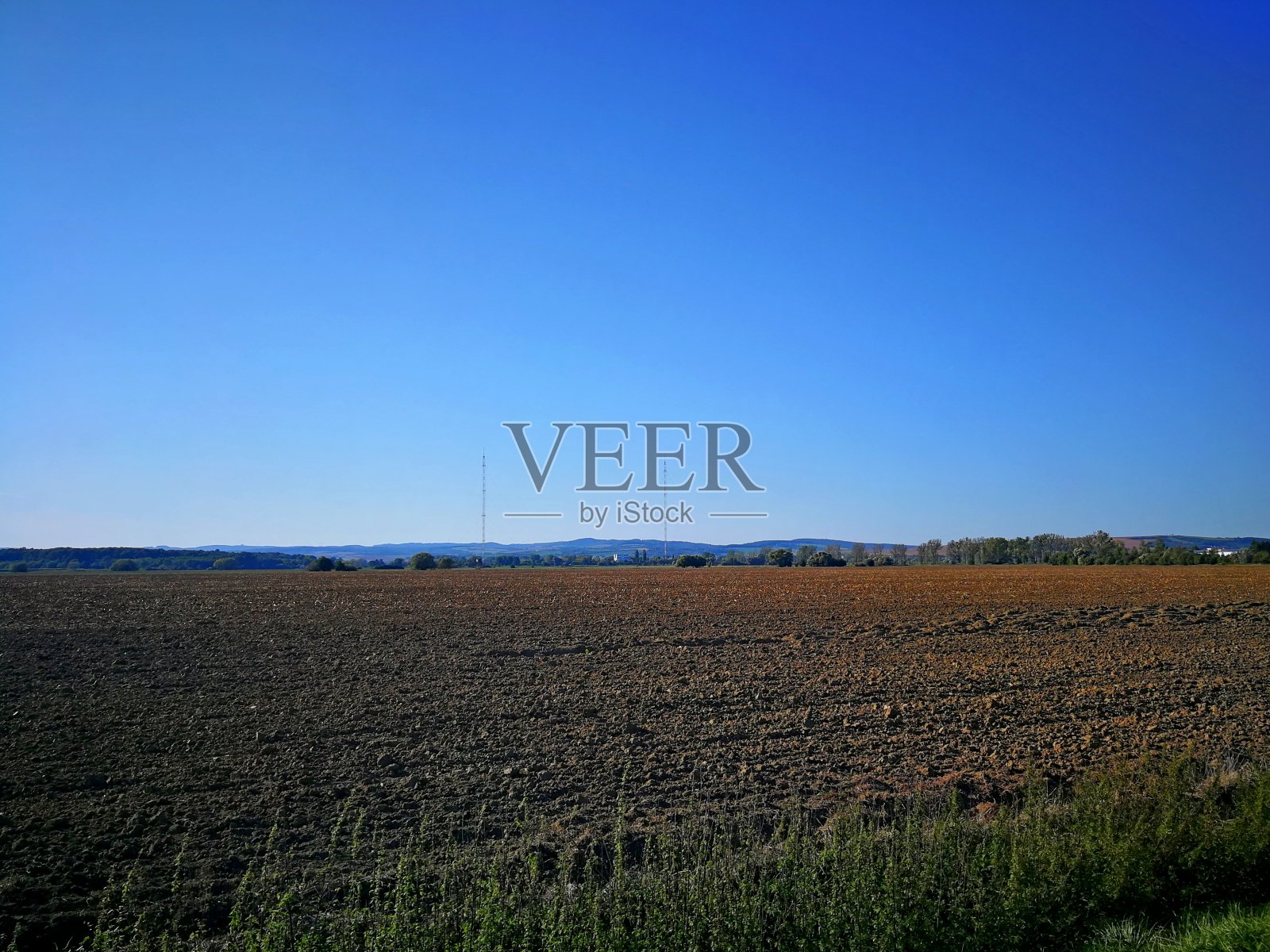 从远处的两根发射机的桅杆上俯瞰耕过的田野照片摄影图片