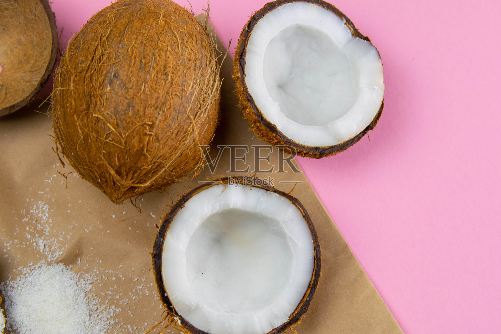 碎椰子在牛皮纸上，站在粉红色的背景上照片摄影图片