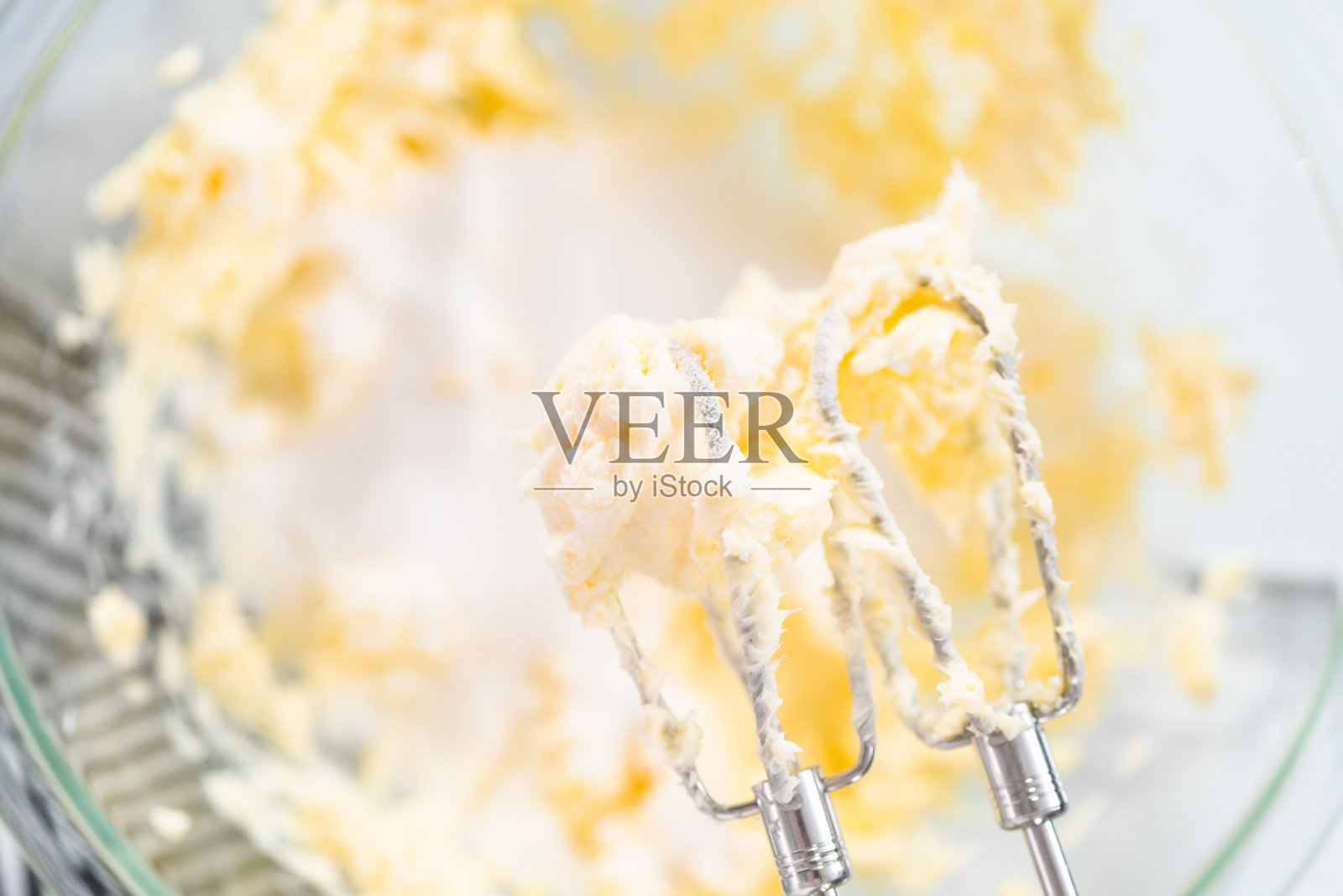 在一个玻璃搅拌碗中混合各种材料来烘焙巧克力饼干。照片摄影图片