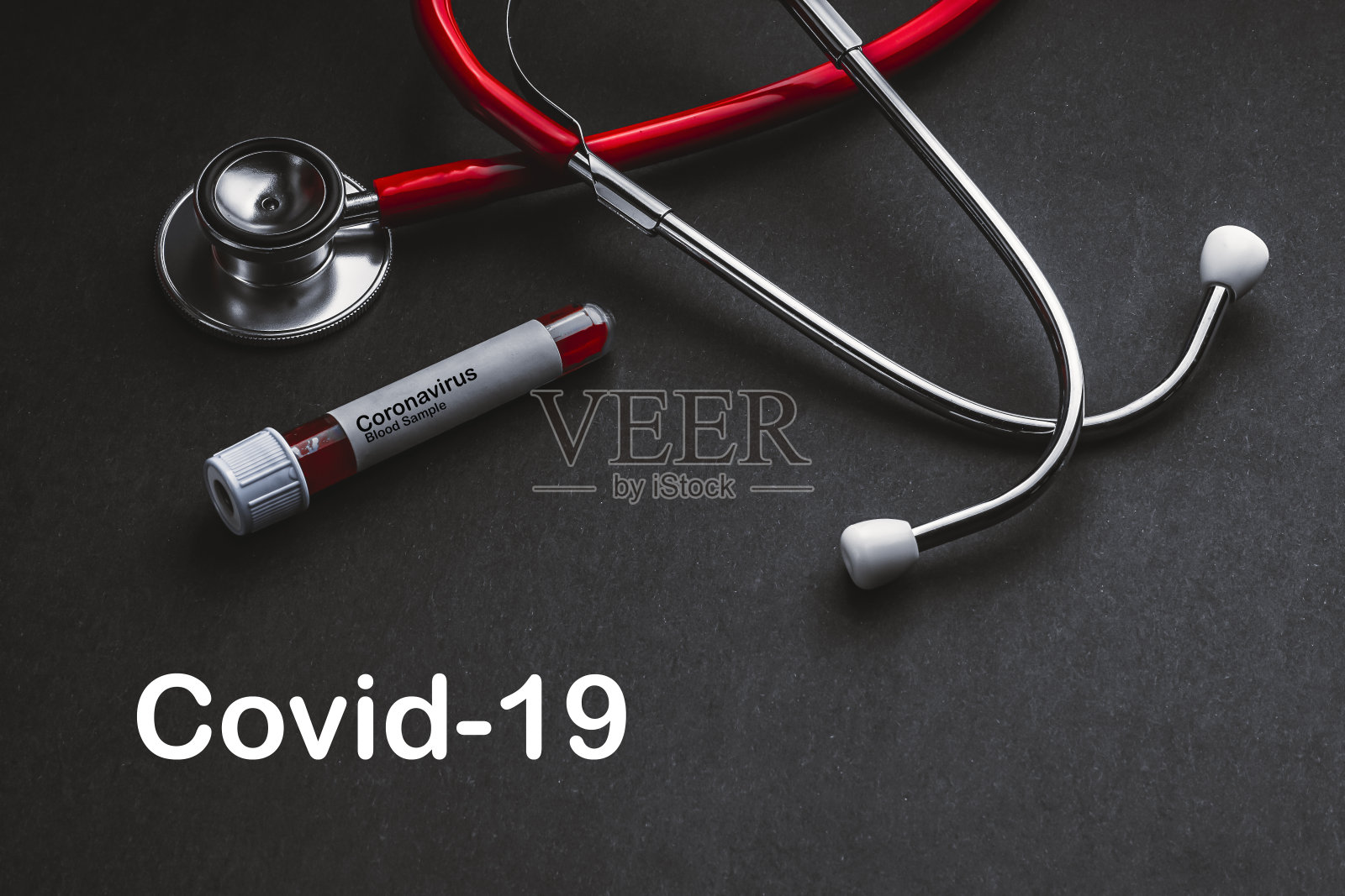 配有听诊器和真空管的COVID-19文本，黑色背景照片摄影图片