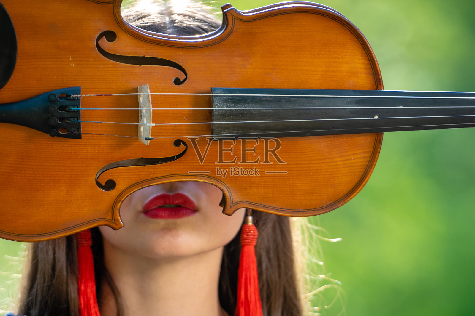 一个积极的年轻女人的肖像。面部的一部分被小提琴的颈部所覆盖照片摄影图片