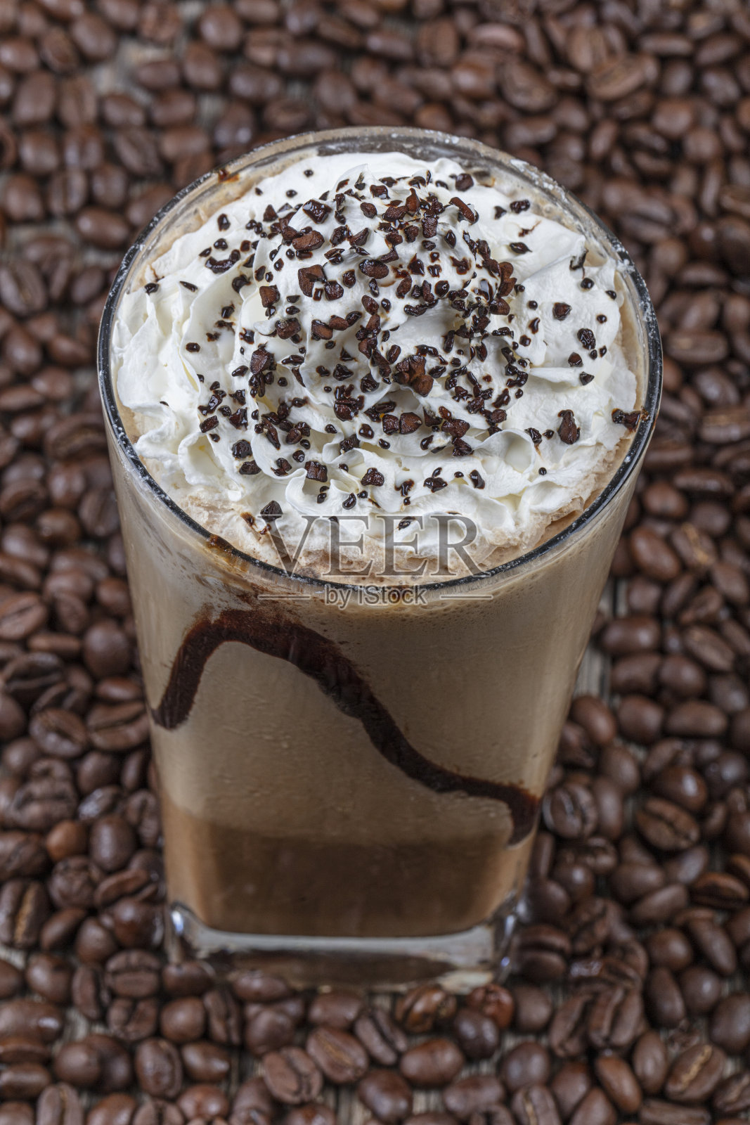 外卖杯里放着冰星冰乐，木桌上放着吸管和咖啡粒。照片摄影图片