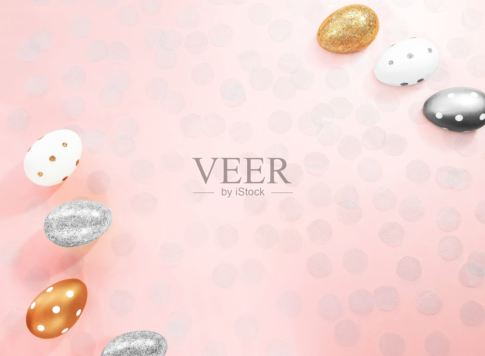 由金色、银色和白色的鸡蛋和薄纱纸屑组成，以柔和的粉红色为背景。复活节假期的广告内容。平放，俯视图，复制空间的文本。照片摄影图片