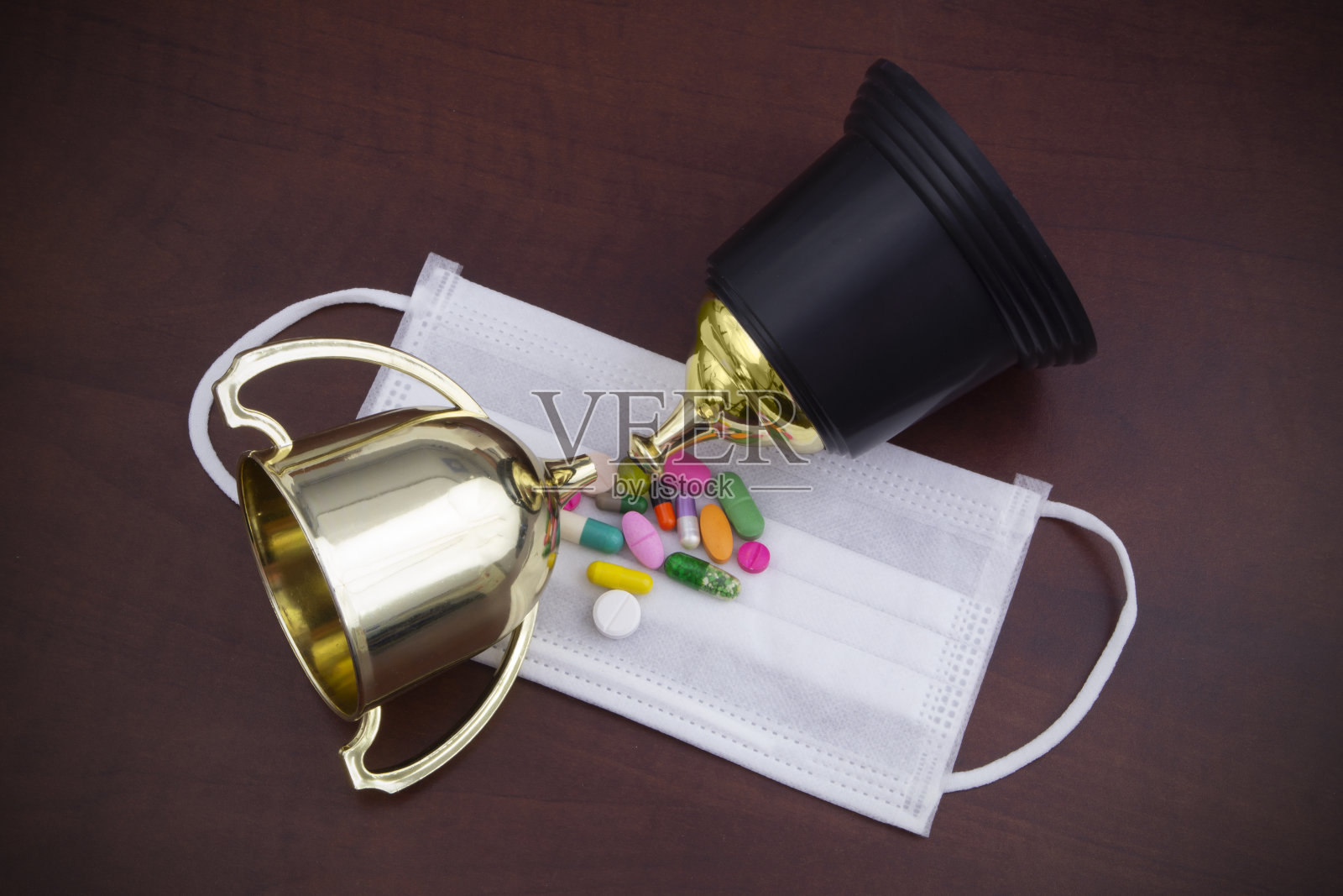 破碎的运动奖杯、个人防护一次性医用口罩和药品。照片摄影图片
