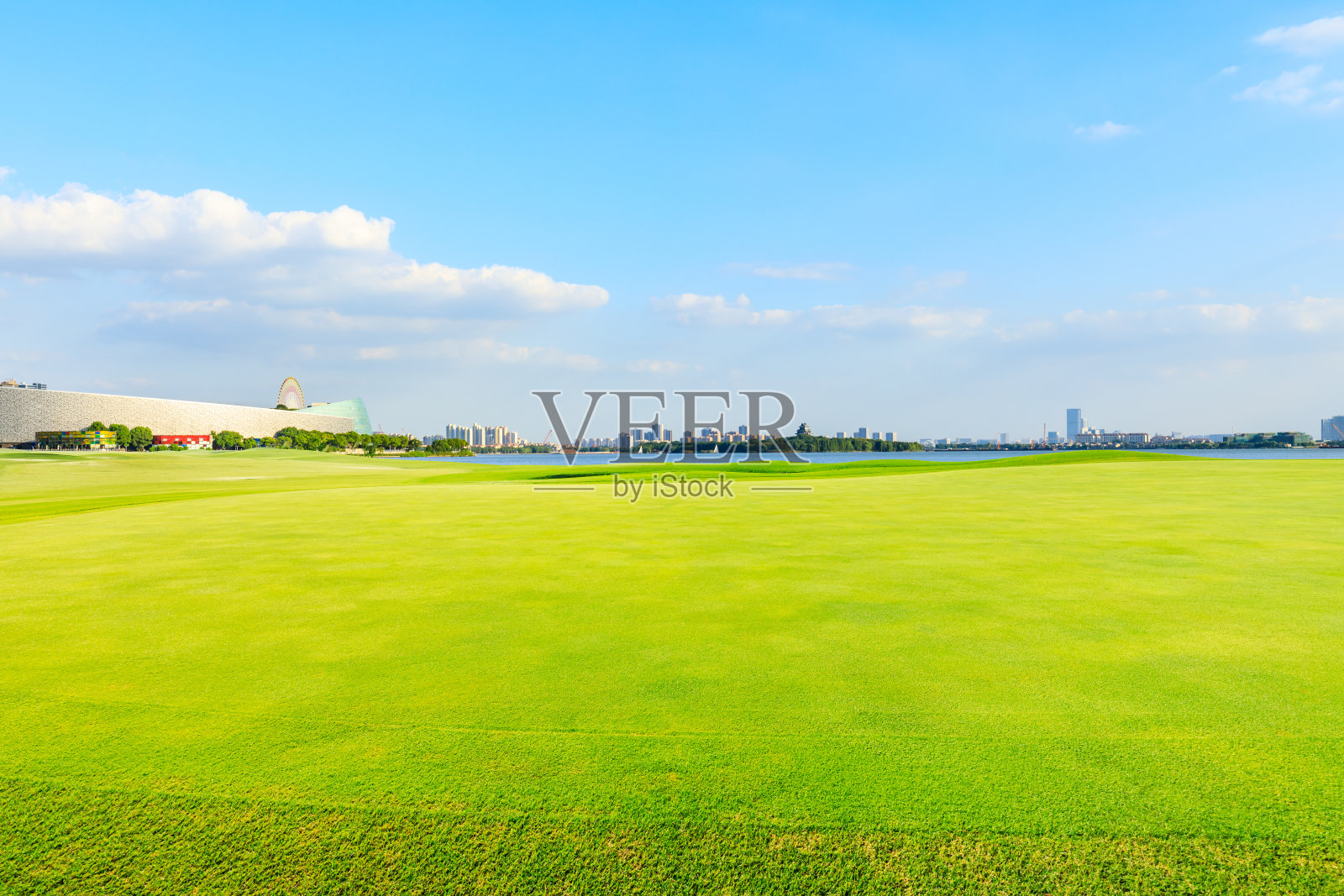 在阳光明媚的日子里，苏州城市的天际线和绿草。照片摄影图片