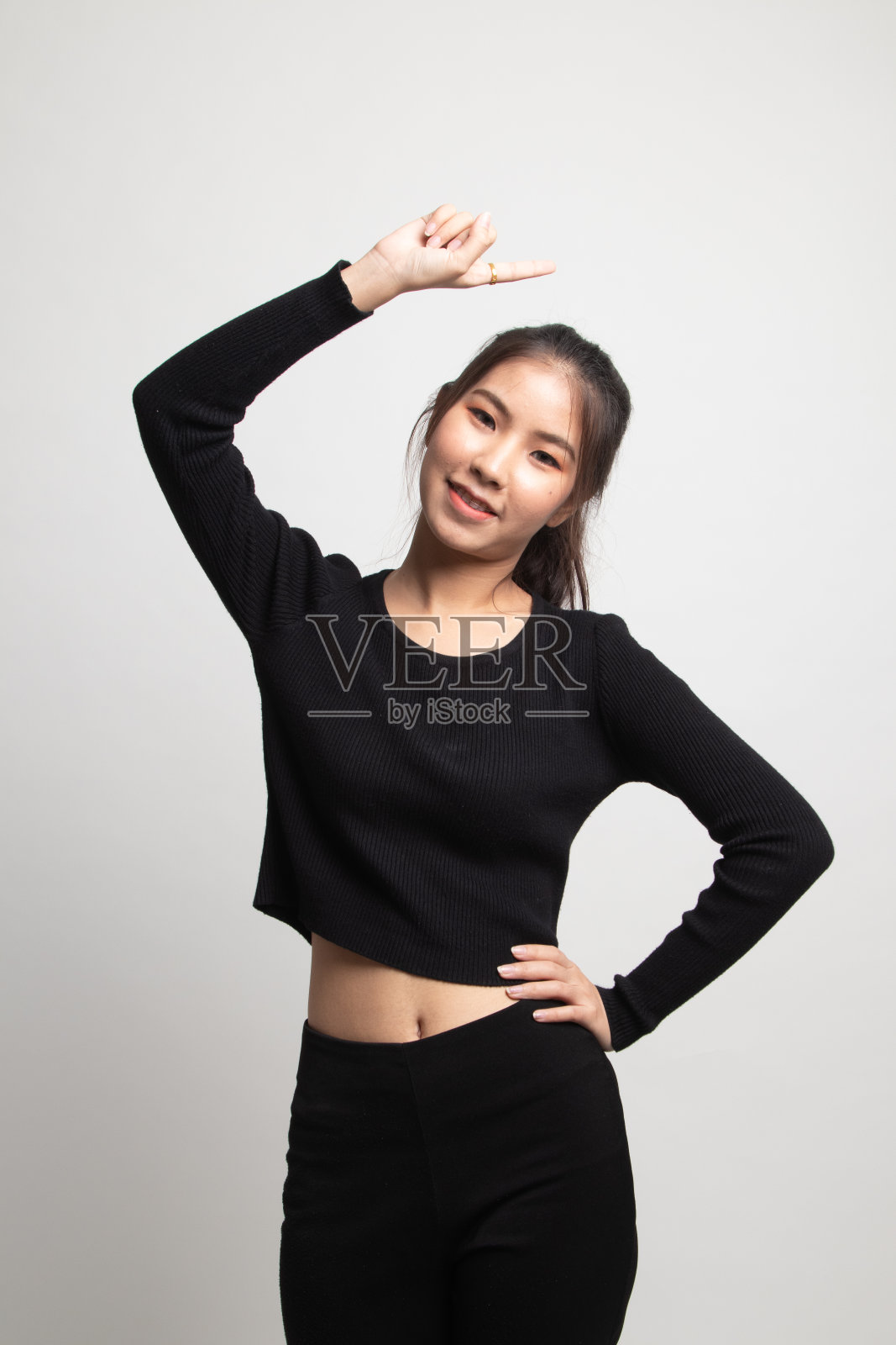 年轻的亚洲女子微笑着向上指。照片摄影图片
