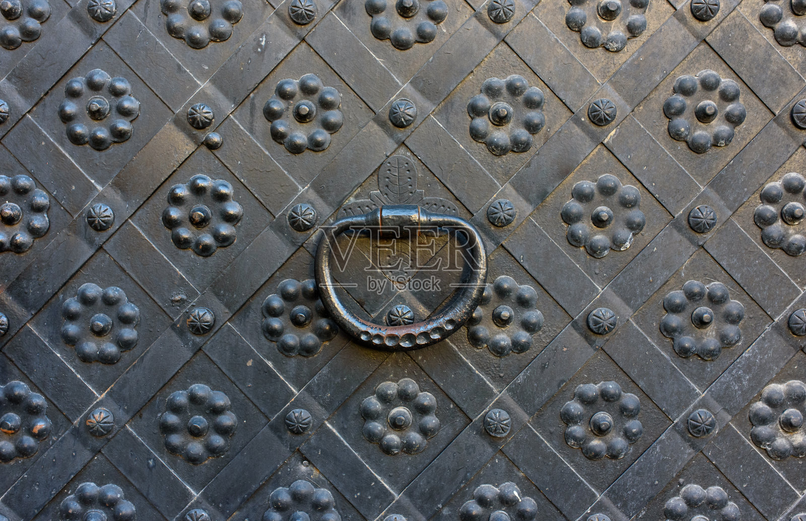 古建筑的建筑装饰元素，一扇古老的金属锻造门和格子门，一个门把手和一个门环。在利沃夫的大街上，公共场所。照片摄影图片