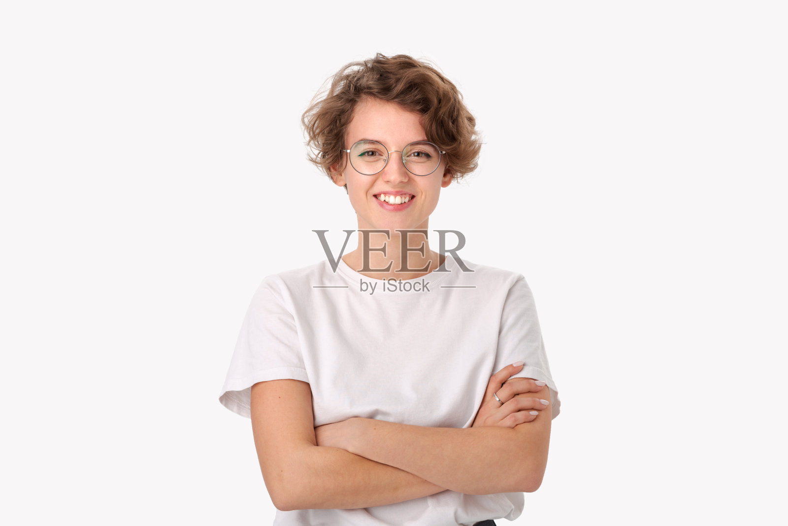 微笑的年轻女人，身穿白衬衫，戴眼镜，看着镜头，双手交叉照片摄影图片