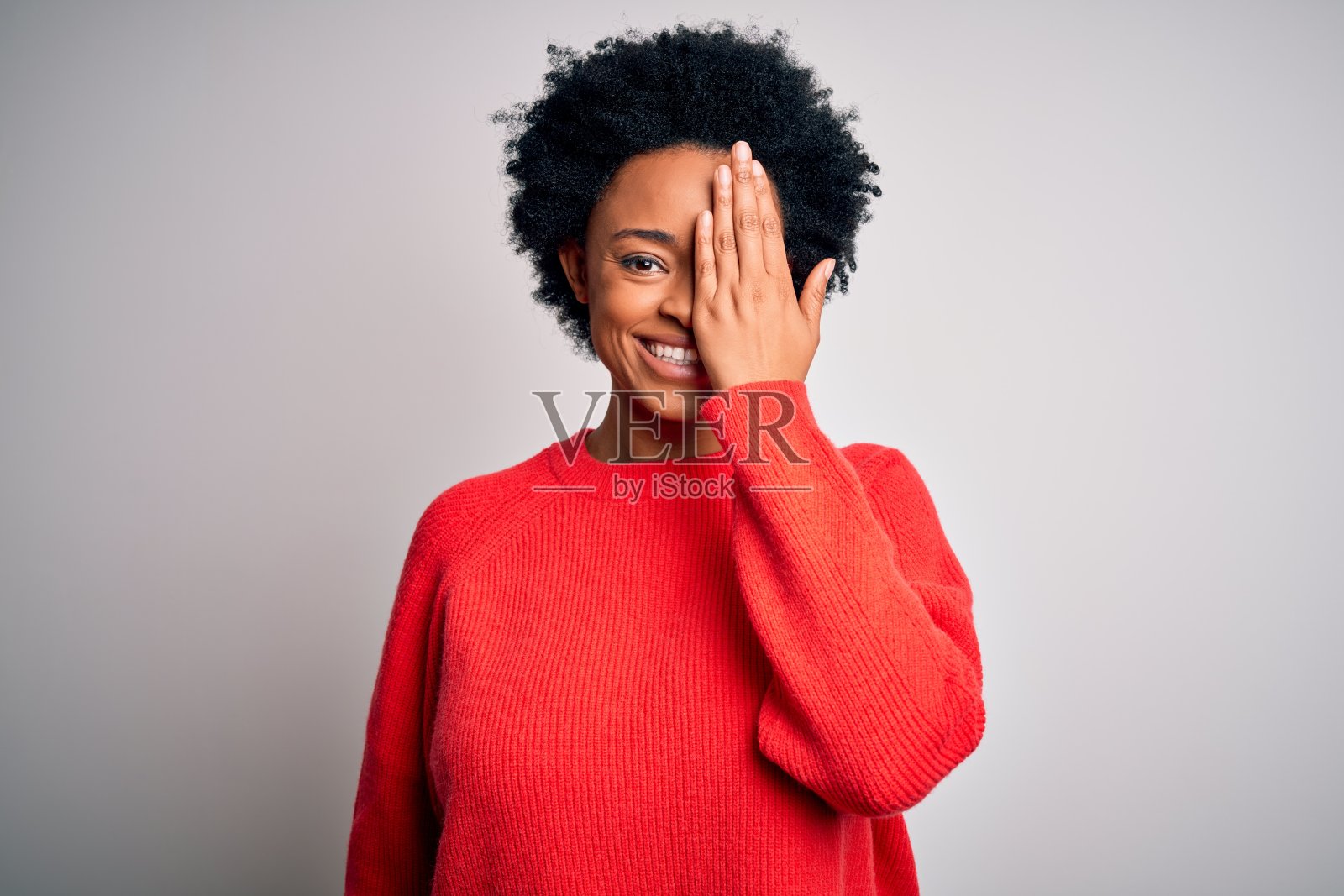 遮住一只眼睛，面带自信微笑和惊讶表情的年轻漂亮非裔卷发女人照片摄影图片